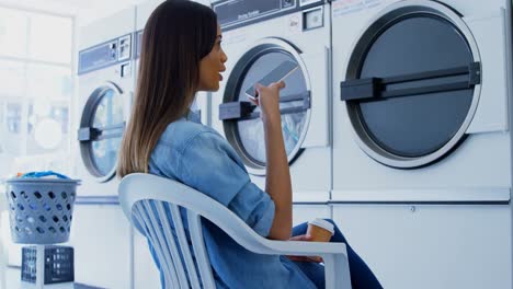 mujer hablando por teléfono móvil en la lavandería 4k