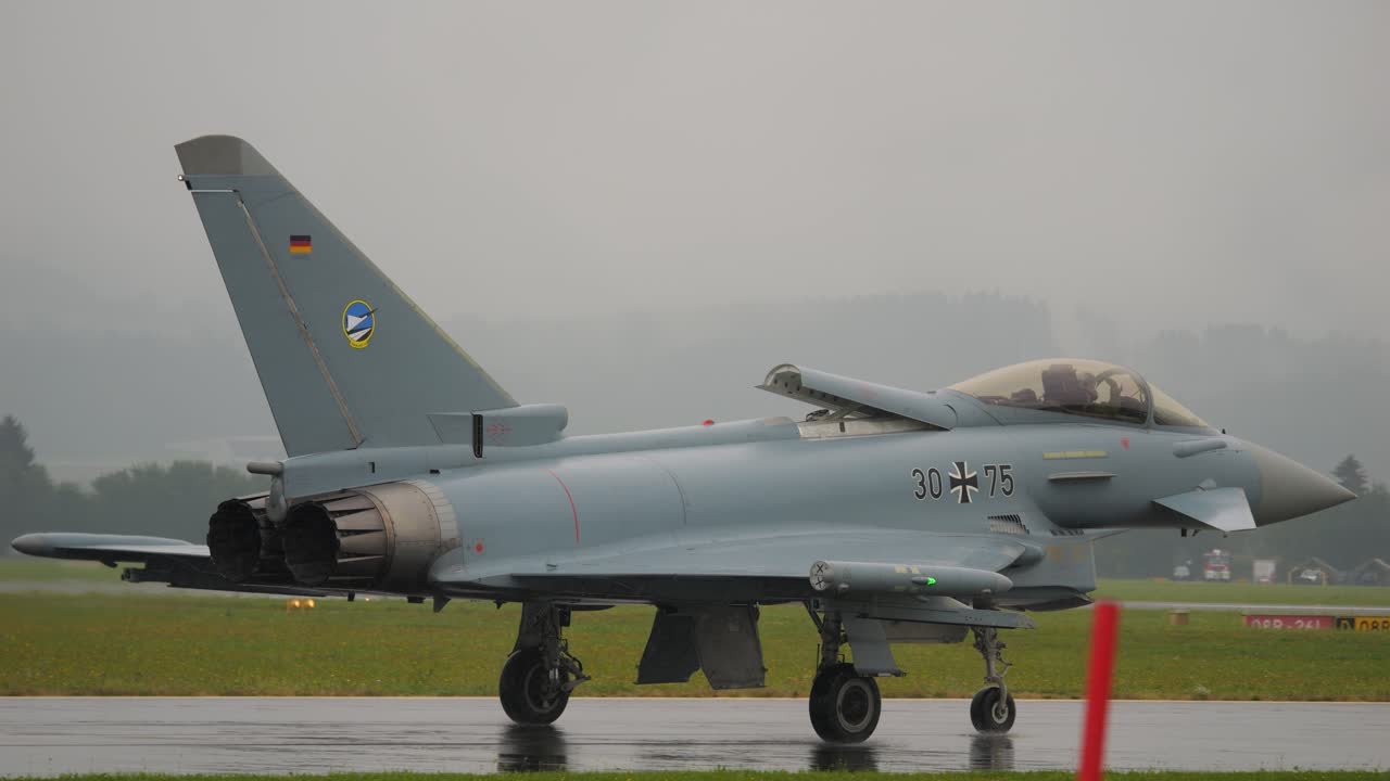 Eurofighter lands on the runway with white smoke trailing behind, flying against a blue sky