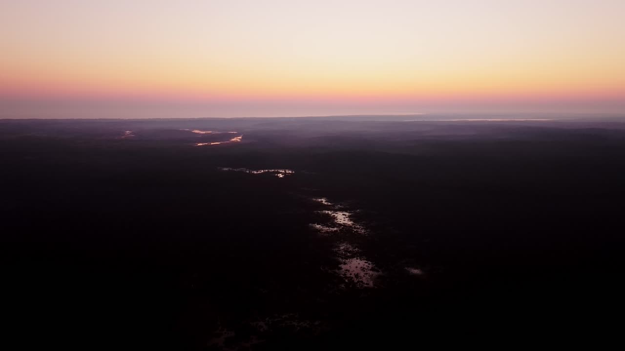 Peaceful bog waters shimmer in early light as drone reverses at sunrise