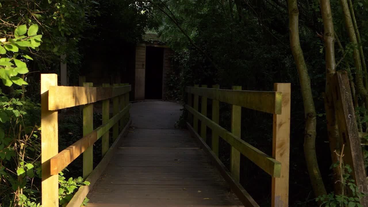 Approaching a small wooden bridge leading to a doorway wide shot