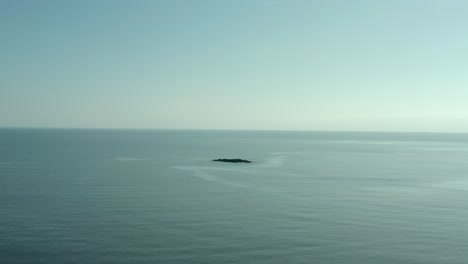 birds eye view of single rock island in middle of nowhere at ocean