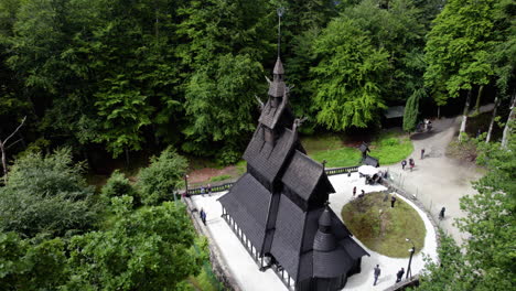 people visiting the fantoft stave church, in sunny norway - circling, drone shot