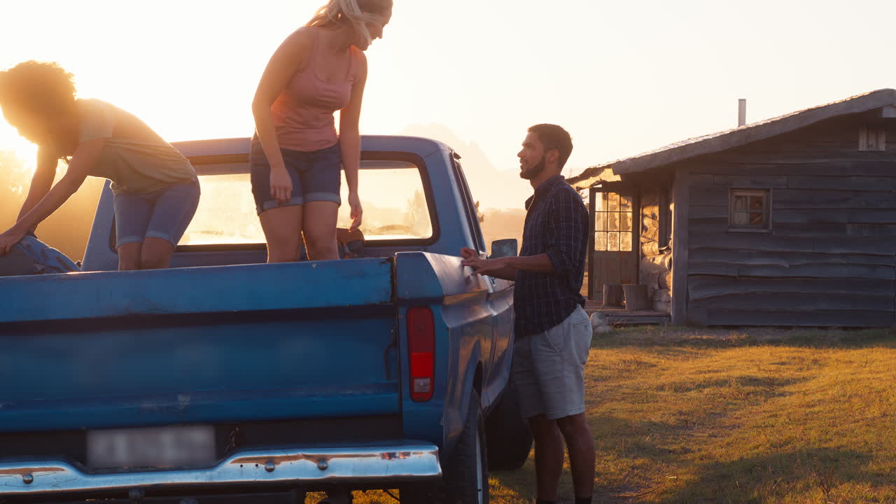 한 무리의 친구 들 이 트럭 에서 배 ⁇  을 풀고 시골 에 있는 오두막 으로 도로 여행 을 하고 있다