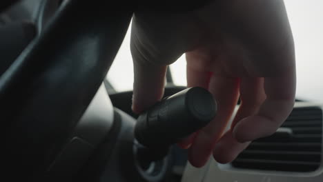 close up of person operating windshield wiper lever on car steering column activating then deactivating wiper function with hand movement