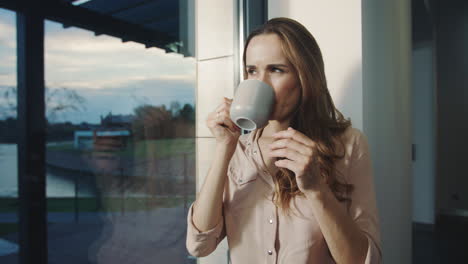 Relaxed-woman-dreaming-near-window-after-working-day.-Pretty-woman-having-rest.