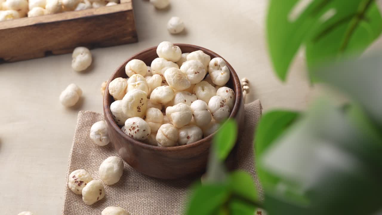 Primo piano di makhana in una ciotola di legno con movimento di zoom tra le foglie