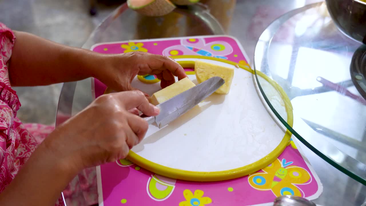 Frau schneidet Ananas in Stücke und überprüft deren Größe.