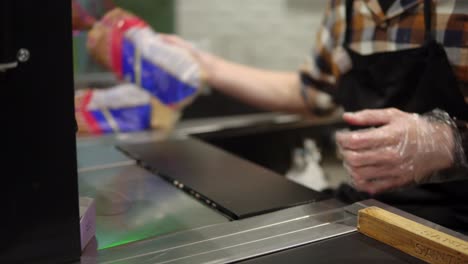 en el supermercado: mostrador de caja manos del cajero escanea comestibles. centro comercial moderno con personal amigable, líneas pequeñas. de cerca