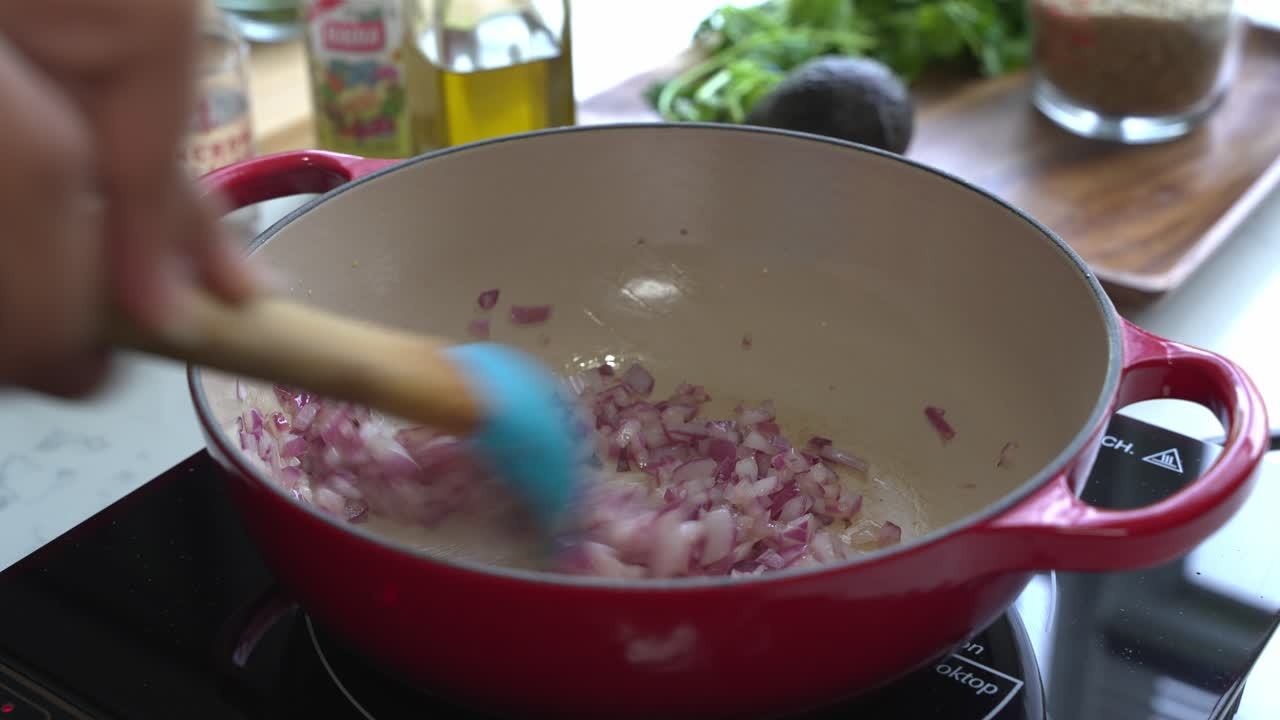 Sweating red onions in a medium sized cast iron pot to cook a meal two cans of beans rice plantain avocado red onion and cilantro