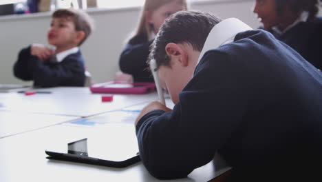 niño pre-adolescente con síndrome de down usando una tableta y un lápiz en una clase de escuela primaria, de cerca