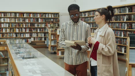 multiethnic man and woman discussing book in library