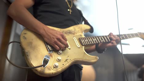 man playing a worn out electric guitar