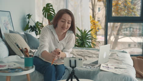 joven artista femenina haciendo transmisión en vivo con un teléfono inteligente