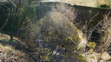 establishing shot of roman bridge crossing navea river as water races below