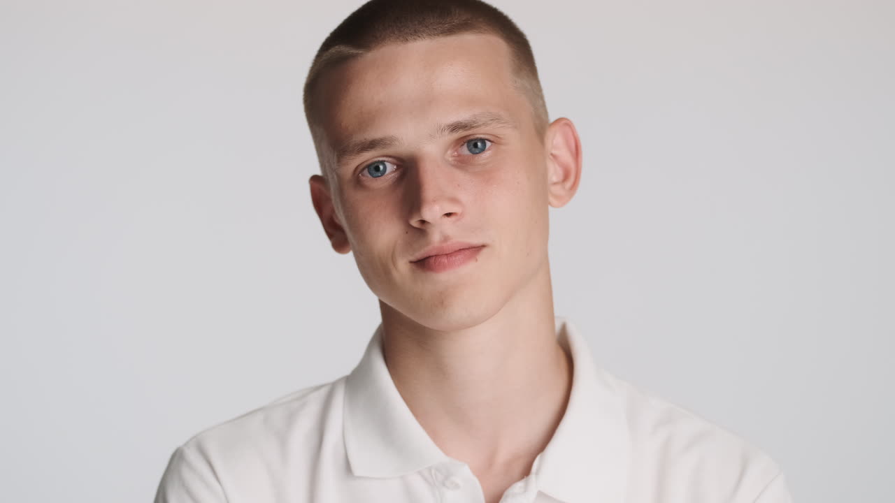 금발의 젊은이가 을 만질 때 포즈를 취하고 있습니다.