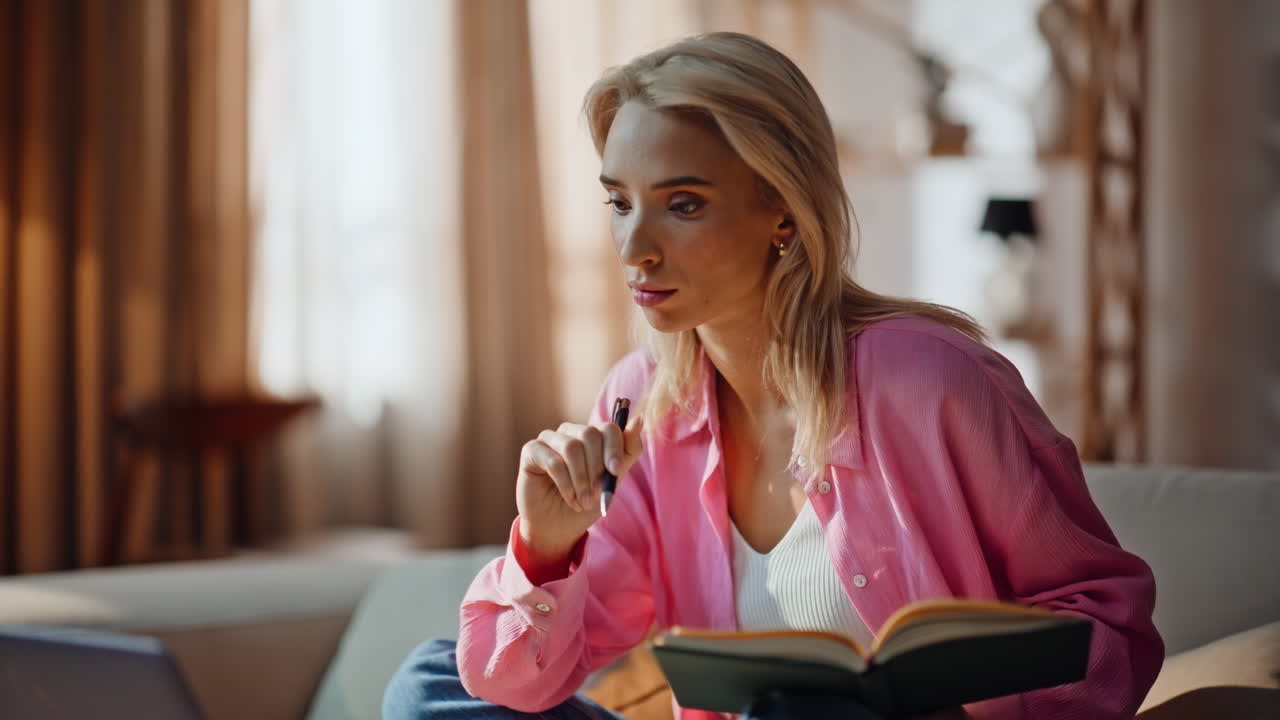 Online student pressing laptop button making notes studying home couch closeup
