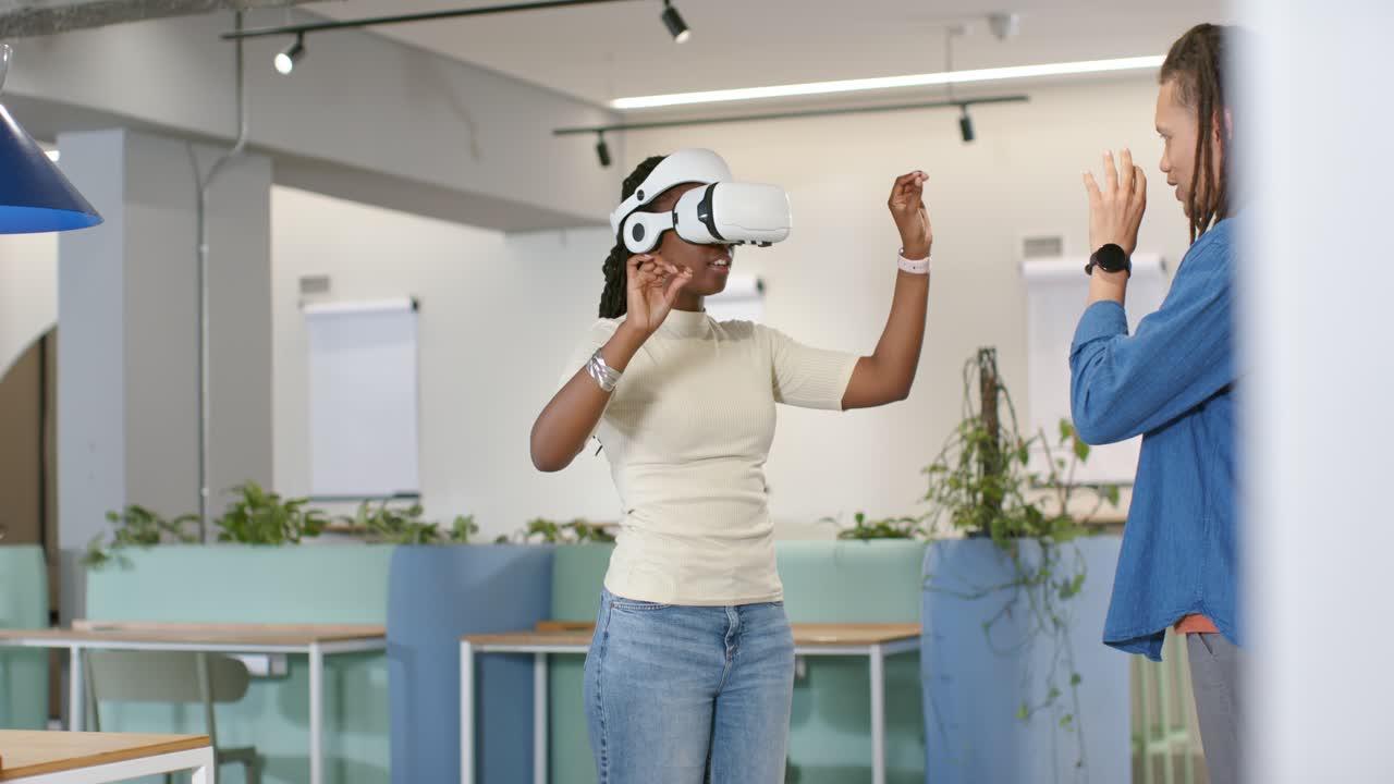 Colleghi afroamericani che osservano una donna con un visore VR che attiva i comandi durante un corso di formazione in ufficio