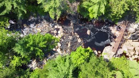 Water-flows-down-river-by-duchesnay-falls-north-bay-ontario-canada,-aerial-top-down-bird's-eye-view