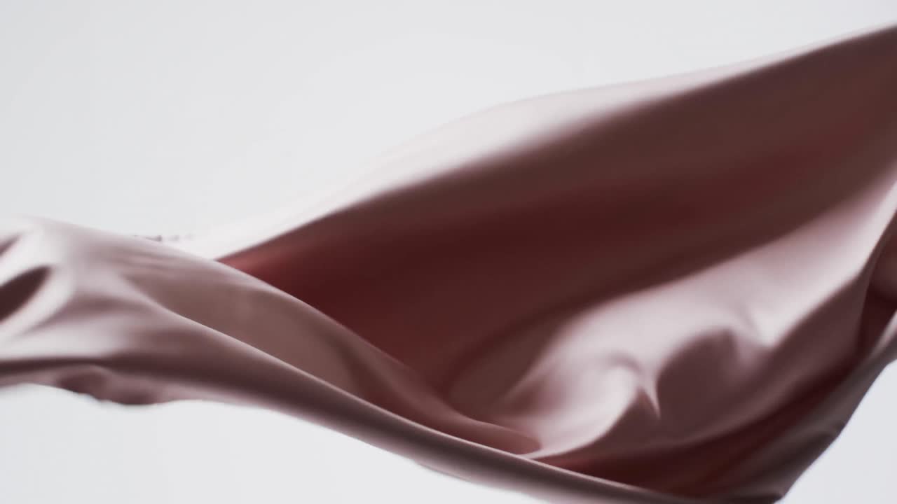 Animation of pink fabric blowing with copy space over white background