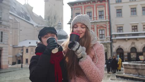 Zwei-Lächelnde-Touristinnen,-Die-Zusammen-Reisen-Und-Heißen-Tee-Und-Kaffee-Aus-Tassen-Auf-Der-Stadtstraße-Trinken