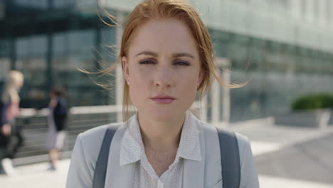 close up portrait of ambitious red head business woman intern looking serious at camera focused and determined in city