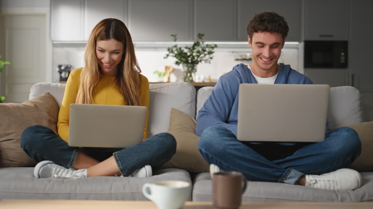 Happy pair working computers couch closeup. Couple looking each other with smile