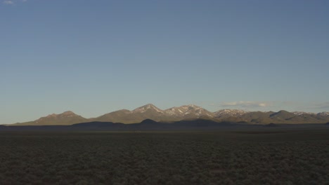 Vorwärtsbewegung-über-Dem-Beifußfeld-Bei-Sonnenuntergang,-Annäherung-An-Weit-Entfernte-Schneebedeckte-Berge