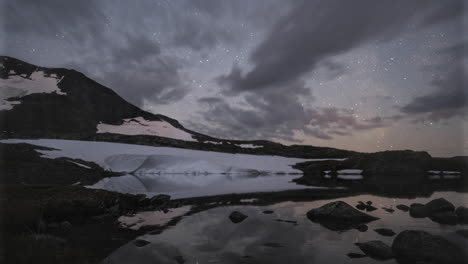 lapso de tiempo de movimiento de la vía láctea sobre el lago glacial en el parque nacional de jotunheimen, noruega
