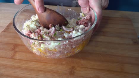 stirring and combining recipe ingredients in a glass bowl on a wooden chopping board