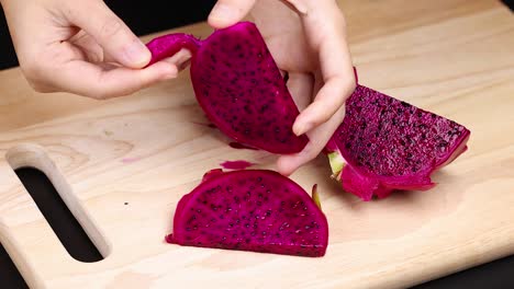 hands peeling dragon fruit on a cutting board