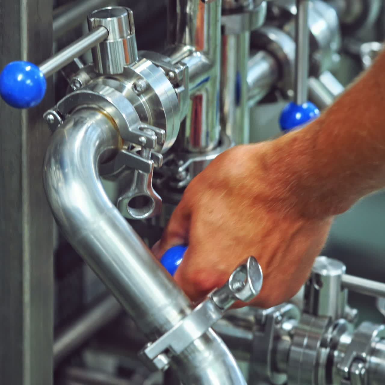 Worker switches on automated machine in a modern plant. Worker turning on metal tool to start the work of a modernized machine in a dairy factory. Close-up.