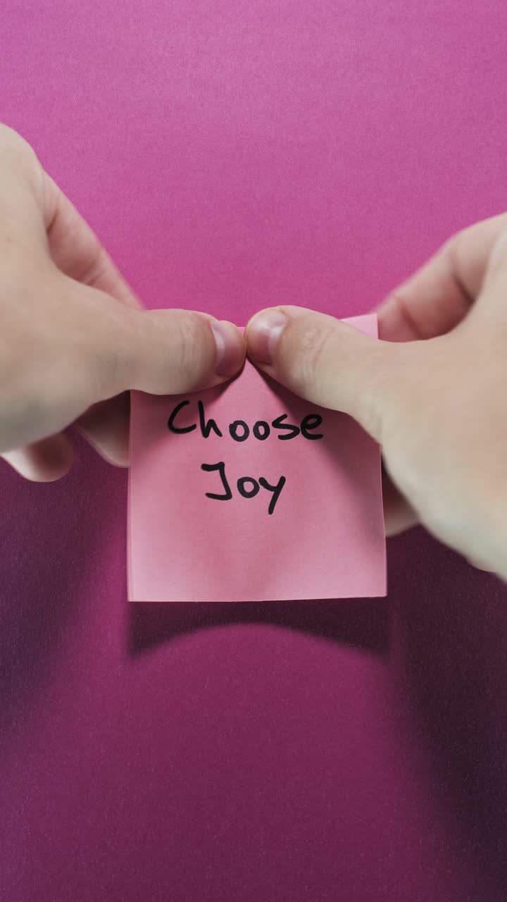 Choose Joy on pink sticky note against vibrant magenta wall, conveying positivity and happiness