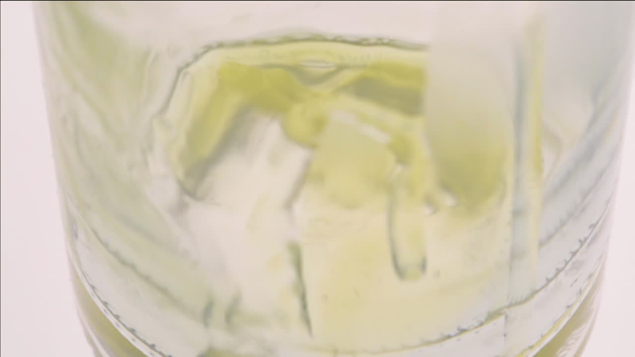 primer plano de un jugo coloreado que se vierte en una botella de vidrio