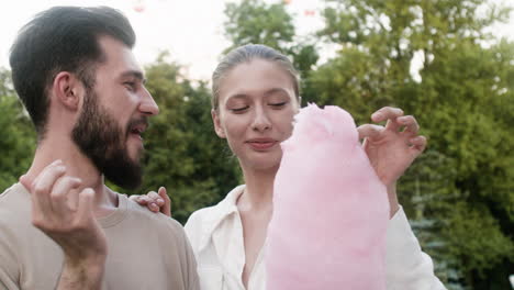 young couple eating delicious cotton candy