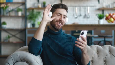 handsome young millennial man, guy wearing headphones, singing, while listening to the music, enjoying his day off, holiday at home. time to have a rest and fun. home leisure activity concept
