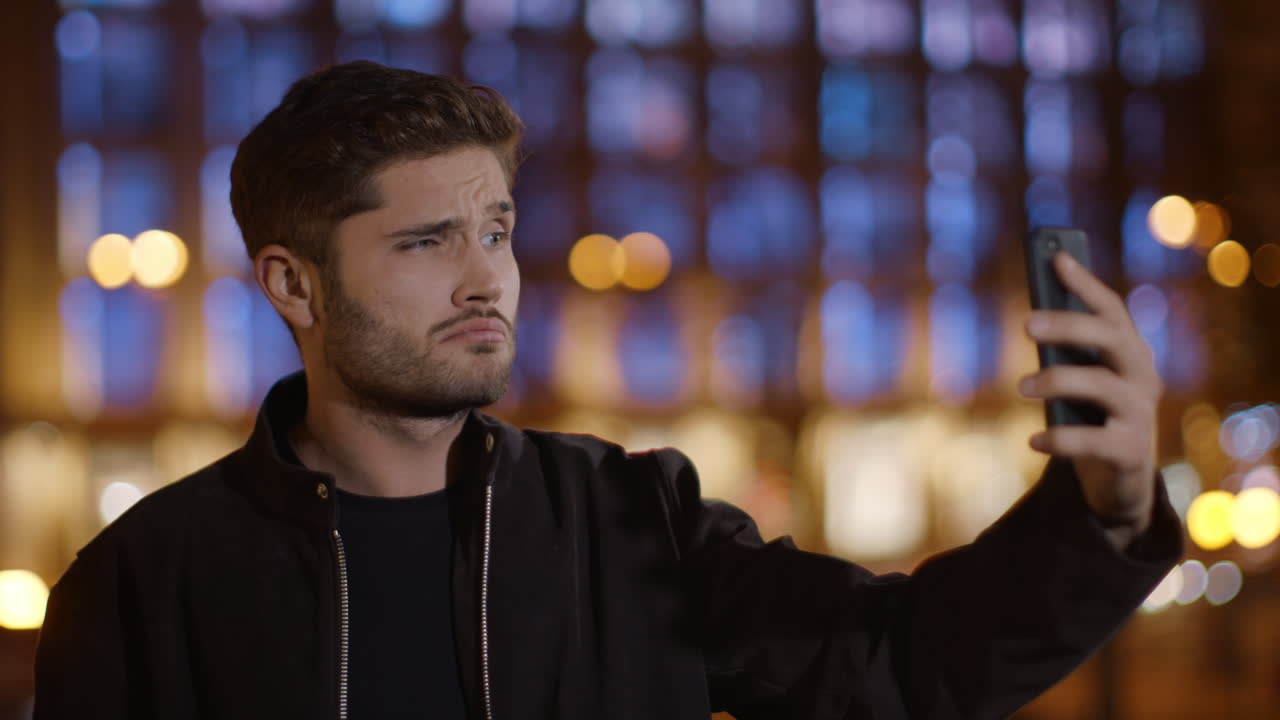 멋진 남자가 야외에서 셀카를 찍고, 재미있는 남자가  ⁇ 드폰 카메라에 혀를 보여준다.