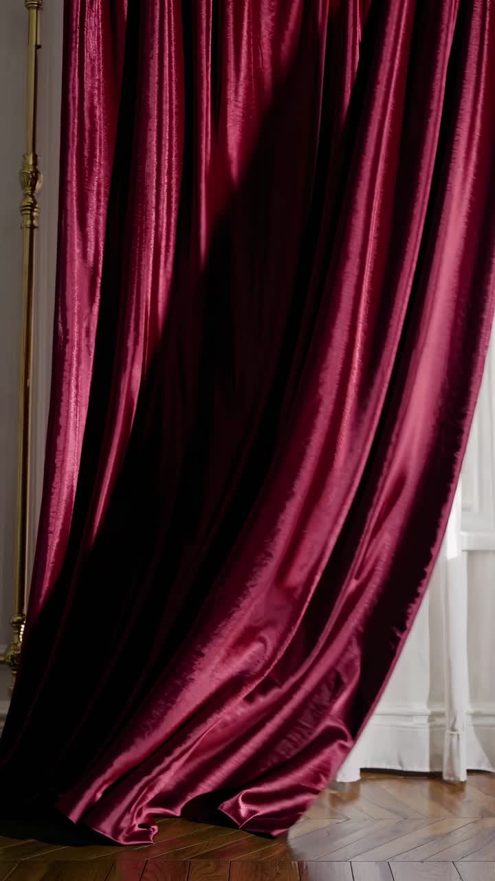 Elegant burgundy velvet curtains drape luxuriously in soft light. Captured from a low angle