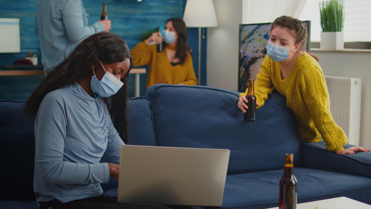 Happy cheerful woman holding beer bottle looking at laptop