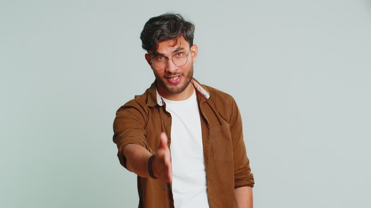 joven indio extendiendo la mano a la cámara, ofreciendo un apretón de mano, saludo, invitación, bienvenida