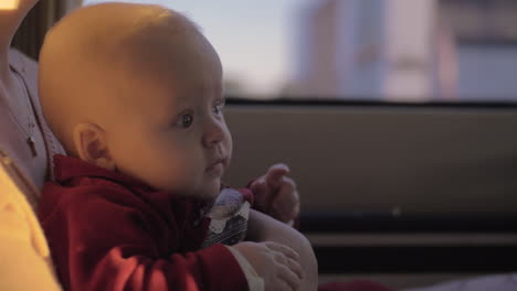 cute baby girl on mother lap in car looking to the road with curiosity