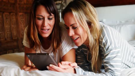 lesbian couple using digital tablet on bed 4k