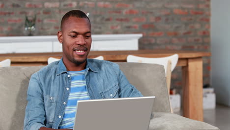 Smiling-student-using-his-laptop