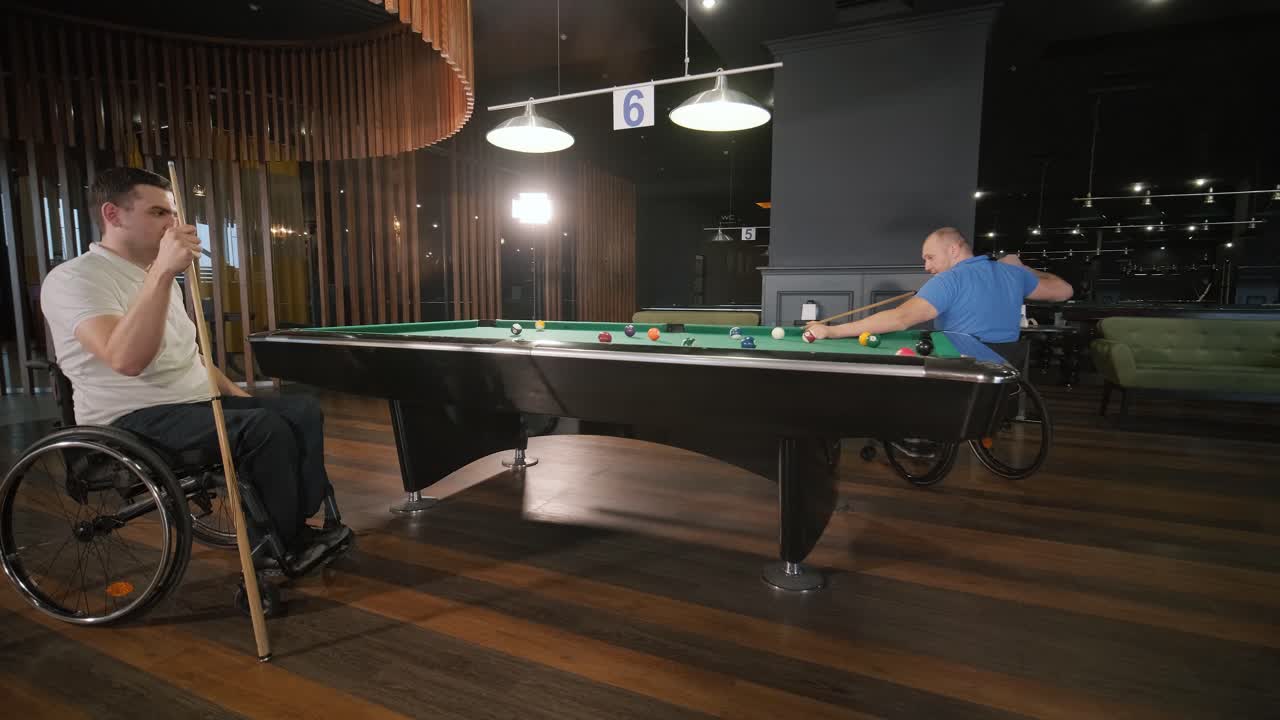 Uomini adulti con disabilità in sedia a rotelle giocano a biliardo nel club