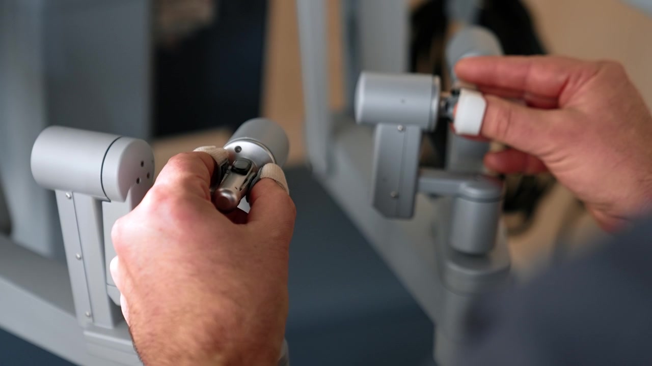 Hands of unrecognized male medic move the manipulators of robotic equipment. Minimal invasive surgery taking place in modern hospital. Close up.