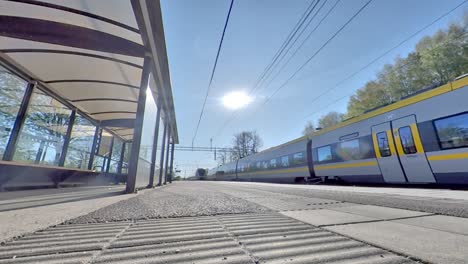 low wide angle of swedish train passing by train stop on sunny morning, gothenburg