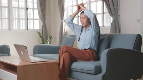 asian woman sitting sofa use laptop computer and relax in home living room, video in 4k