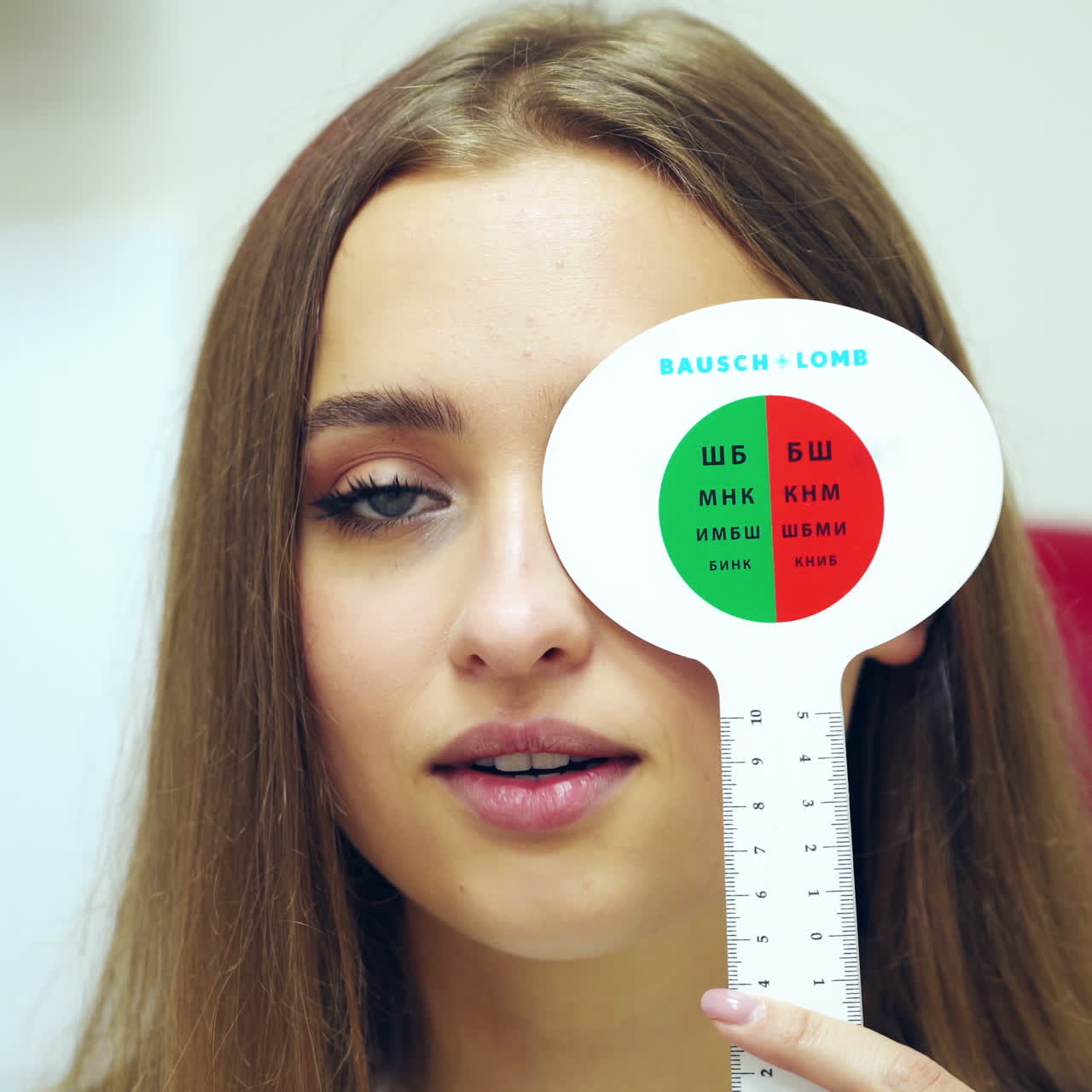 Ophthalmology concept.Young woman covering her eyes one by one during her visit to optometrist. Beautiful female doing vision test with occluder.