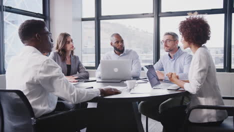 female manager and corporate business colleagues talk in a meeting room, close up