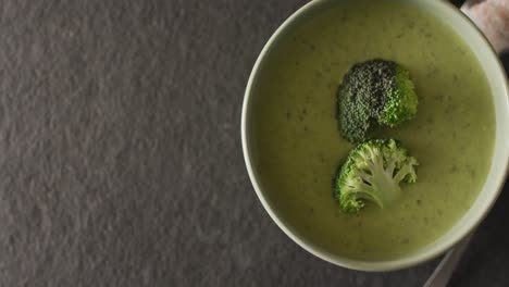 video of cream broccoli soup in bowl on grey table with spoon and spices