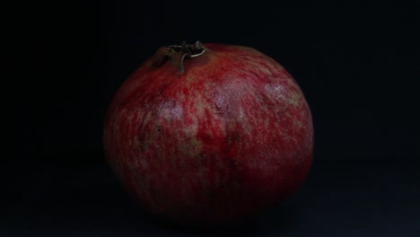 Pomegranate-fruit-on-the-black-background-is-illuminated-by-moving-light